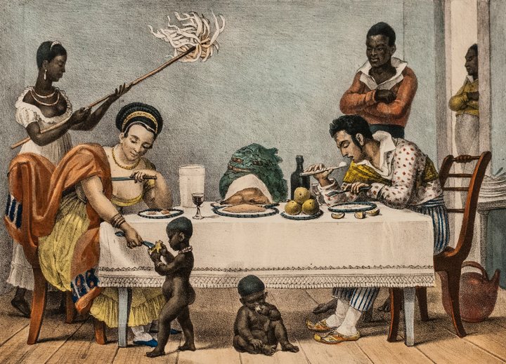 Litografia de Debret: um casal janta numa casa do Rio de Janeiro, no século XIX, servido por pessoas escravizadas; duas crianças negras estão junto à mesa, uma delas sentada no chão.